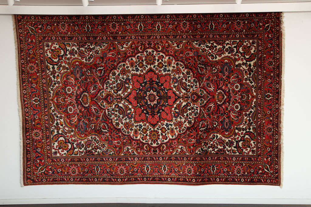This Persian Bakhtiari carpet consists of handspun wool and vegetable dyes, circa 1920. The pile is hand-knotted and in excellent condition, with vibrant colors of red, blue and bright cream throughout the medallion, field and border. This carpet