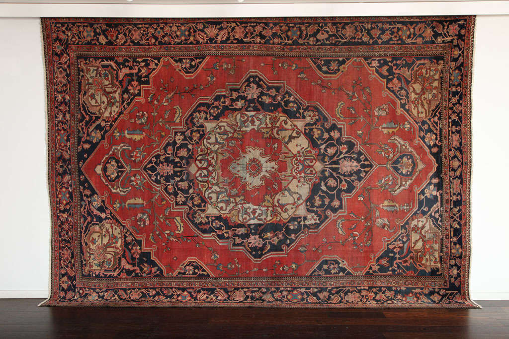 This Persian Fereghan carpet circa 1880 in handspun wool and vegetable dyes was completed using a hand-knotted pile with cotton warp and thread. Its deep navy and red medallion design is offset by an intricate border, with light blue and cream