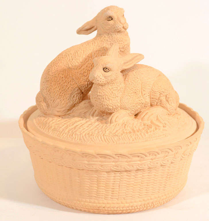 A molded Caneware game pie dish in the form of a woven basket with two rabbits seated on the cover. The maker used an unglazed surface to create a soft looking texture which evokes the rabbit's soft fur.
Caneware is an unglazed stoneware. In the