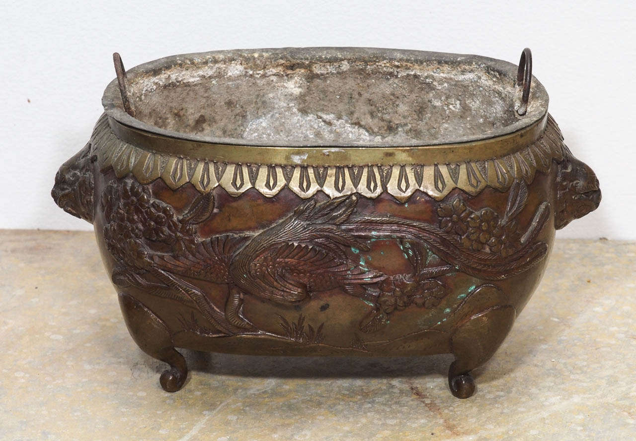 A 19c. Japanese bronze vessel on small scrolled feet and animal masks.  Fitted with a tin liner with handles.