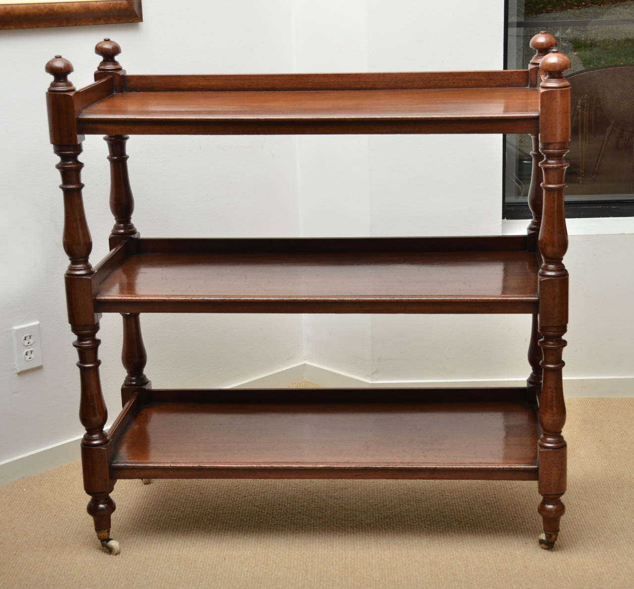Early 19th century, three tier mahogany server with molded edge, turned supports, turned finials, original china casters.