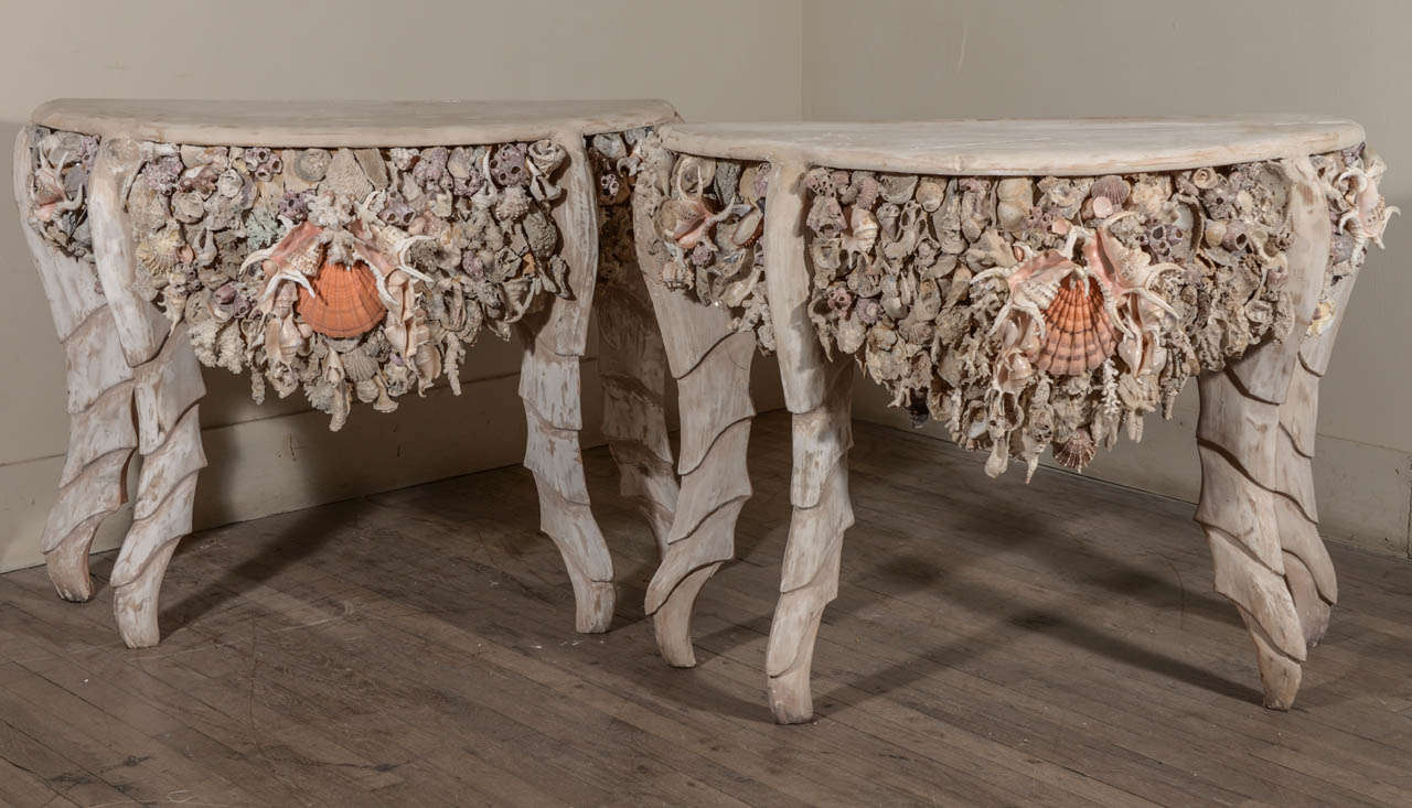 One-of-a-kind pair of carved and painted wooden demi-lune consoles with shell and coral decoration.
