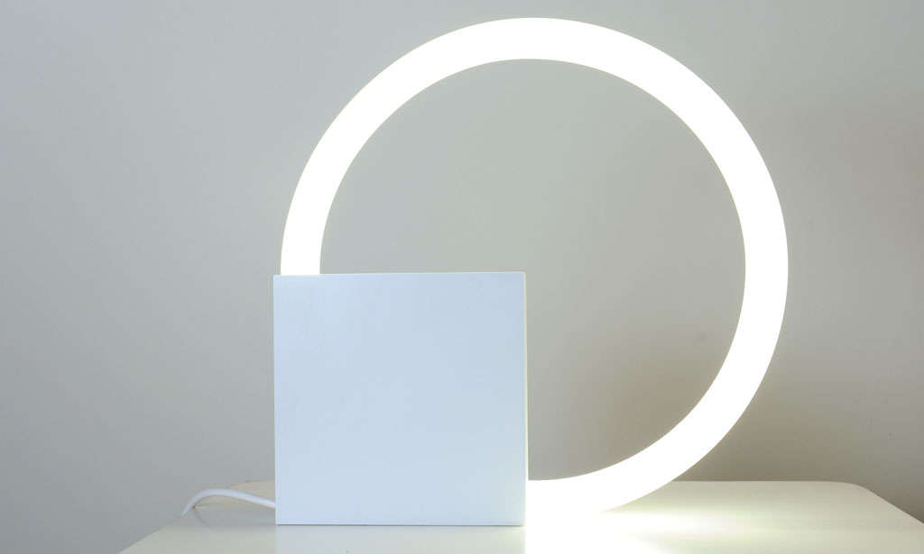 Truly iconic and one of the most famous examples  of minimalist Dutch design, designed in 1968 by Aldo van den Nieuwelaar. 
It is a steel case in which a circular neon light is mounted. It is a table light but also suited as wall mount light. This