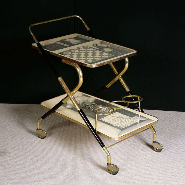 An early Trolley by Piero Fornasetti and possibly Gio Ponti.
The trolley veneered in lacquer with brass and displaying the stylistic genre of Gio Ponti.
The inset panels depicting 