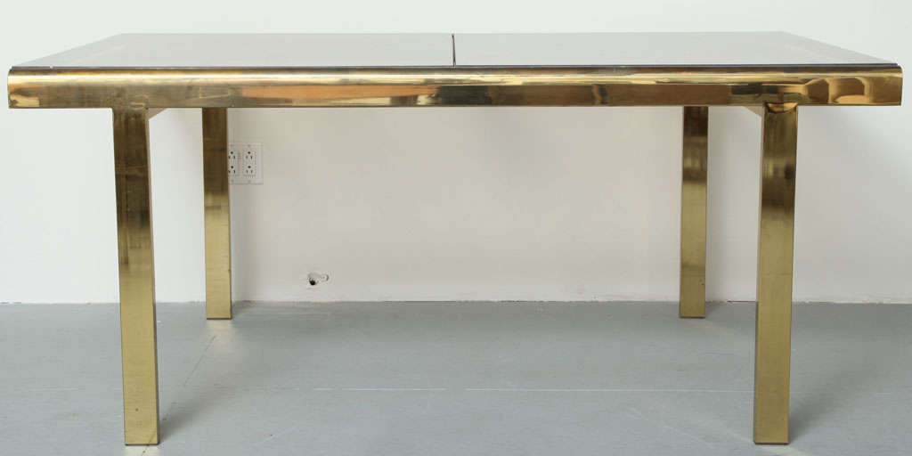 Dining table in brass finish with smoke glass top featuring a self extending top. Made by Design Industries of America (DIA) in the style of Milo Baughman. USA, circa 1970.

Table measures 66 inches in length and extends to 98 inches in length,