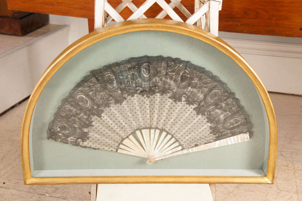 Midnight black lace and gauze fan. Mother-of-pearl struts. In fan shaped shadow
box gilded frame. Fan size 12" x 22.25".