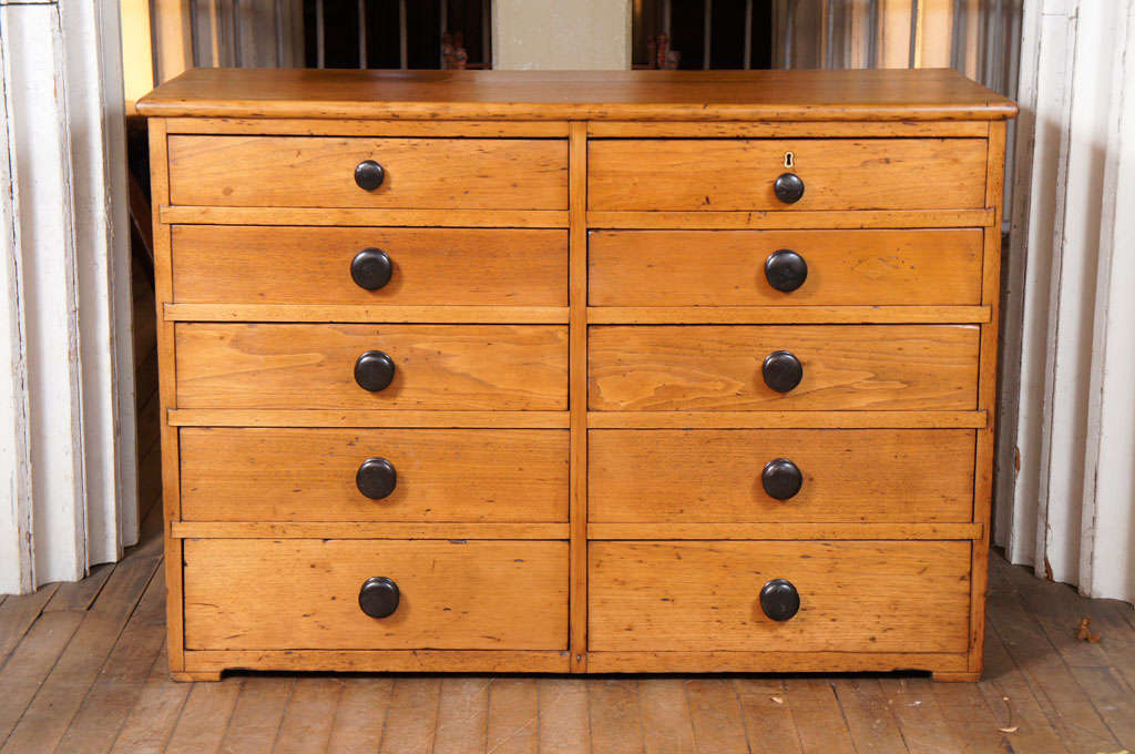 double graduated bank of drawers - dovetail construction - black wood knobs - one locking drawer - on square pad feet - in butternut - possibly Shaker - is more of a blonde color than as it appears here