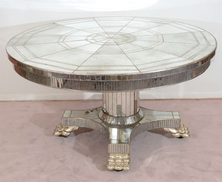 A vintage dining table covered in tiled mirrors. The pedestal base has claw-form feet and casters.