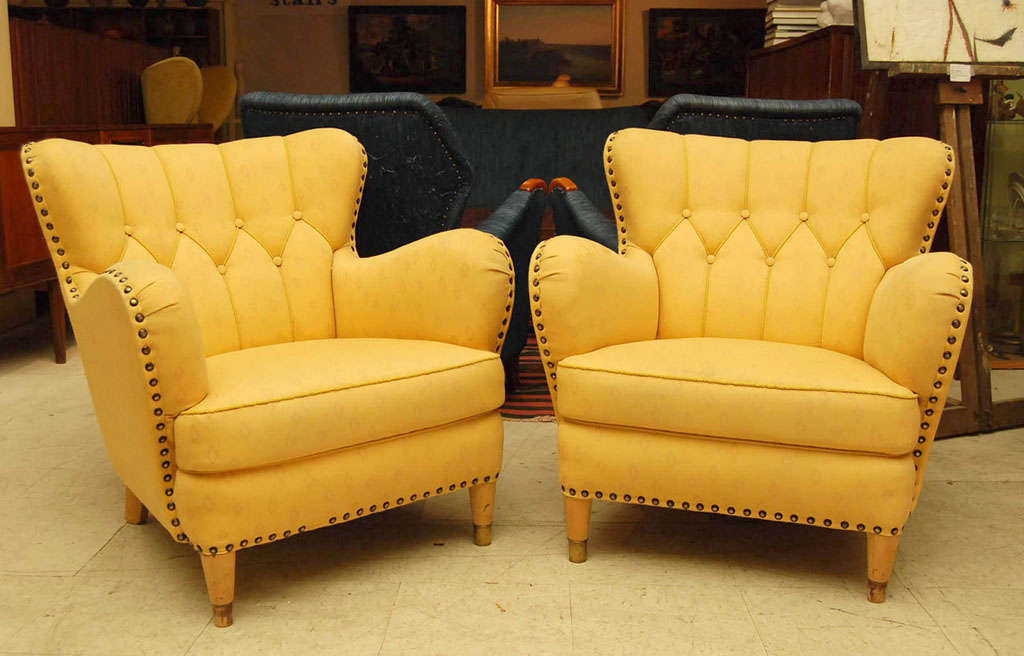 Pair of club chairs upholstered in yellow fabric with large brass studs,with turned beech legs, mid-century modern