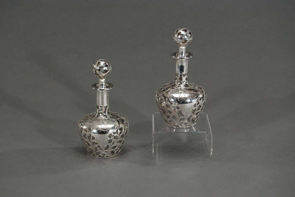This pair of hand blown crystal perfume bottles are beautifully decorated with sterling silver overlay in an all-over Art Nouveau swirling decoration. Thickly applied, these perfumes bottles exhibit America's finest silver work and are further