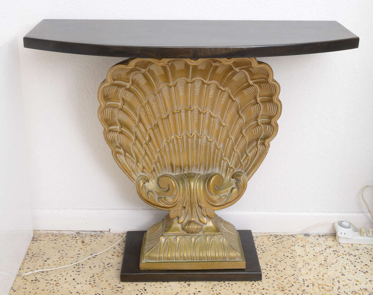 This beautiful Hollywood Regency style console table it by the iconic Grosfeld House furniture company. The piece is composed of a demilune shaped top and plinth base in mahogany wood that has been recently refinished. The scalloped shell is in