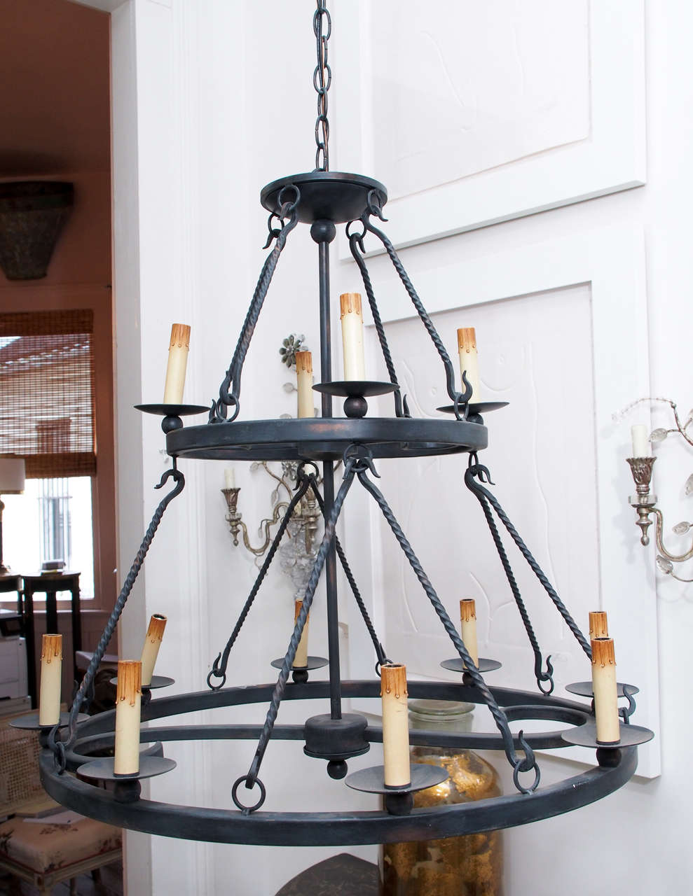 These black wrought iron chandeliers are a reproduction of an antique. Consists of two circles, the top being smaller than the bottom, giving it a cone shape.  On the top of the bottom tier, there are 8 candles that screw in lightbulbs fit into. The