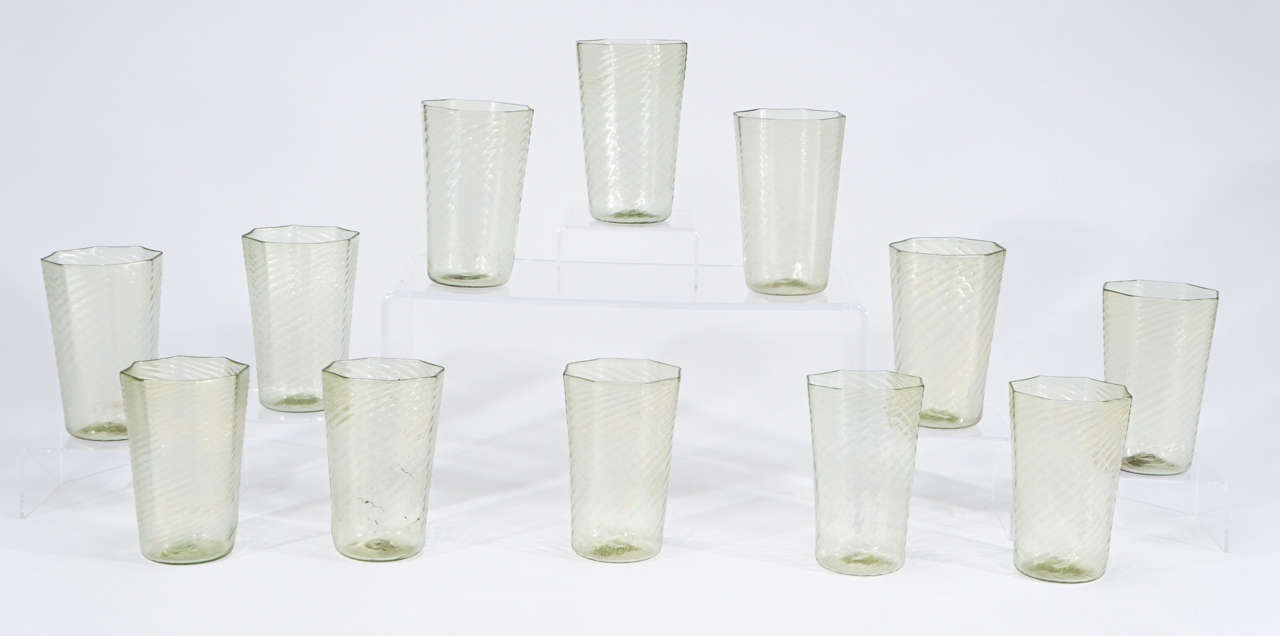 This is a wonderful set of 12 Salviati hand blown tumblers in a pale green and gold color. The lovely optic swirl highlights the octagonal shape which feel great in the hand and their nice large size serves as a perfect water goblet. The gold leaf