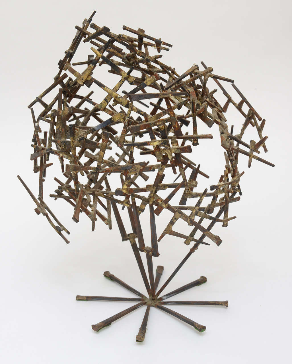 Gilded cement nails going in all directions make this one of a kind tabletop Brutalist abstract sculpture interesting. it looked like a globe where to go and in which direction; an abstraction indeed! One can attribute this in so many ways. The