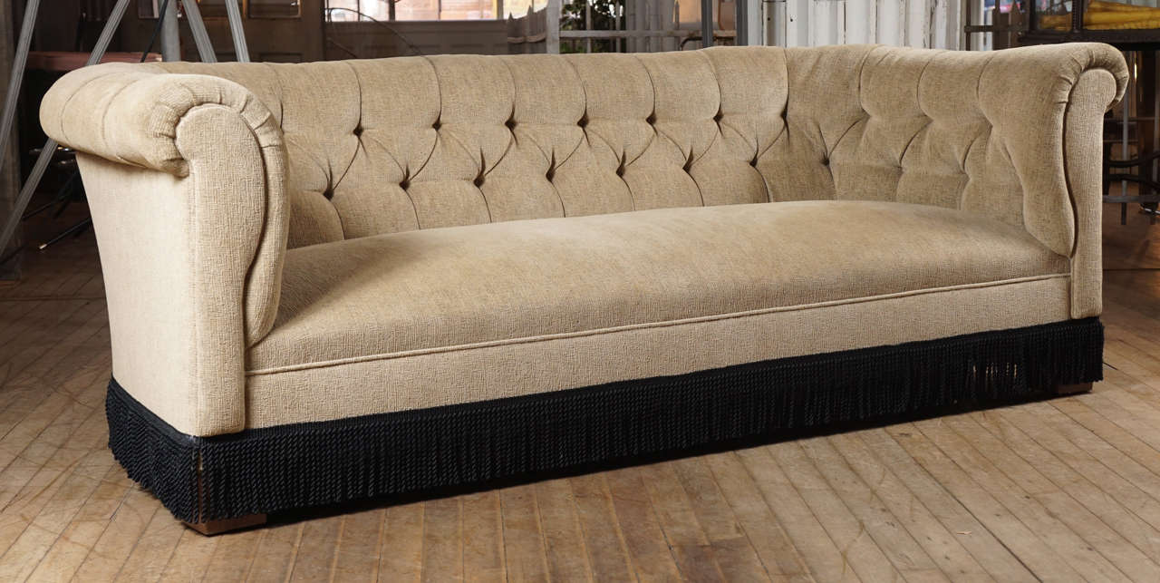 Extremely comfortable pair of chesterfield style sofas, textured camel color upholstery and black fringe trim