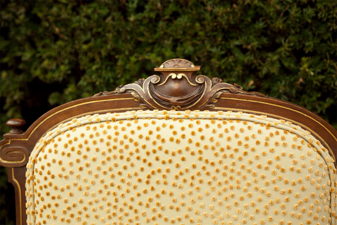 A pair of 19th century French Napoleon III style chairs featuring a detailed crest consisting of a heraldic shield, surrounded by acanthus leaves, all gilted trim. Recovered.