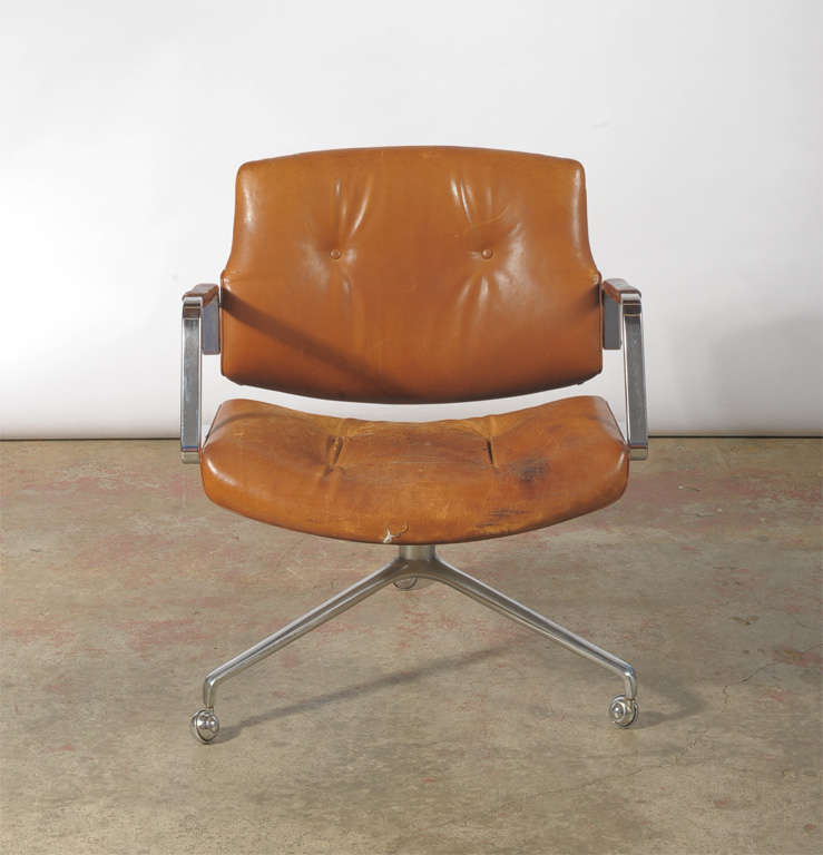 Lounge chair. Seat, back and armrests upholstered in buttoned cognac leather, patina to the leather, matte chromed steel three-star foot, on castors. Produced by Kill International.