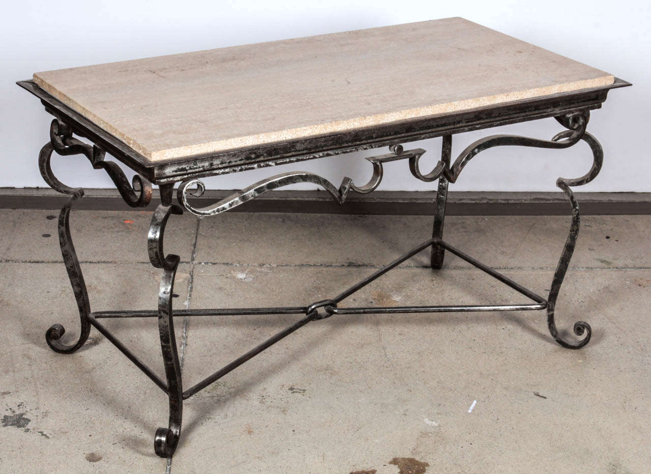 This hand-polished wrought iron coffee table features an original travertine top, reminiscent of the style of Gilbert Poillerat. Originating from France in the 1940s, this coffee table carries a sense of history and elegance.

Maintaining very good
