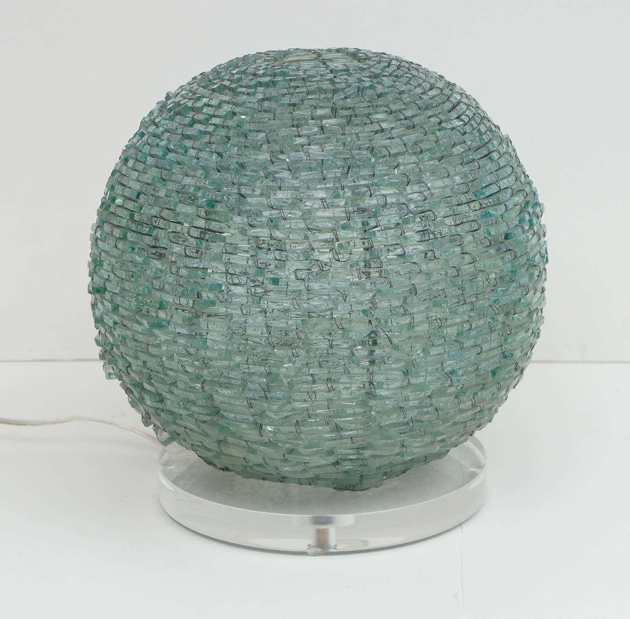 A spectacular spherical table lamp created with 1/4 inch pieces of glass. 
A wire frame sits on a Lucite base.