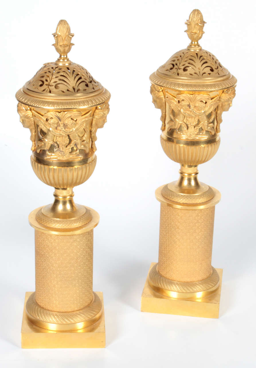 Pair of French First Empire period gilt bronze cassolettes, made for the Russian market. They have a perforated cover to emit perfumes and can also function as a candleholder. They are finely chased with two-toned matte and burnished doré bronze