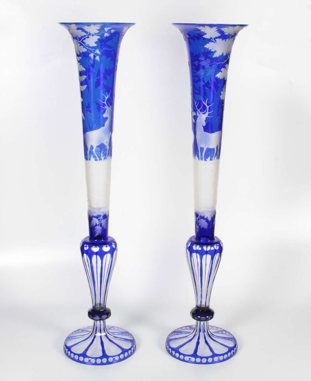 Magnificent pair of palatial double overlay cobalt blue over clear Bohemian crystal trumpet-shaped vases, hand engraved with scenes of stags in a forest; attributed to August Bohm. The stags are deeply carved with magnificent details to demonstrate
