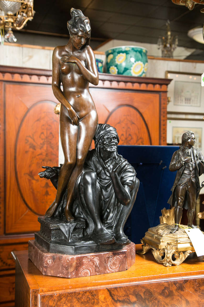 This is a reproduction in two-tone bronze on a marble base.
It is signed but unintelligible. The female in a light brown patina, the slave trader with a darker patina.