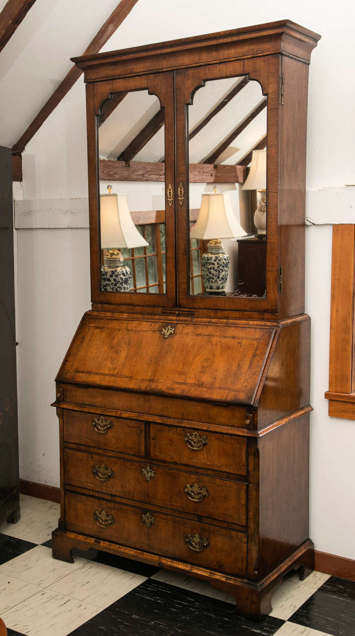 This Queen Anne style bureau bookcase / secretary with mirror doors was reproduced sometime in the latter half of the 19th century, but hews close to the original look and feel of a period original. The fully outfitted interior desk features a