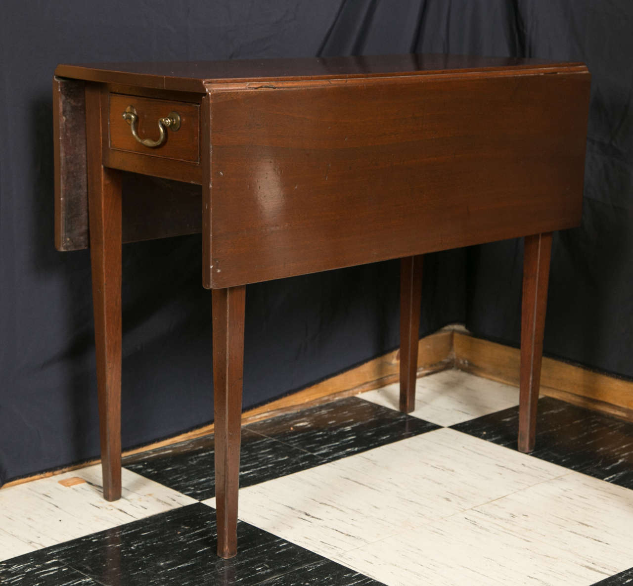 This solid walnut, swing-leg end table has great proportions and would look as well behind a loveseat as it would next to it. Measures: With both 10.75” leaves up, it opens to a near-square 34” x 35.5” and a functional drawer at each end adds