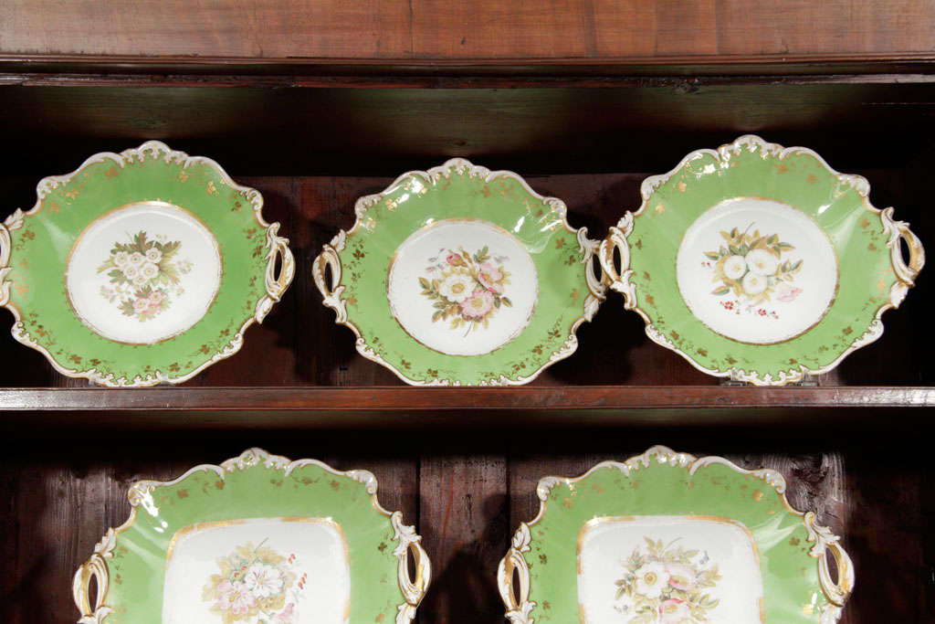 English, porcelain partial dessert set circa 1850 with floral bouquets within a gilt enhanced apple green scrolled border.