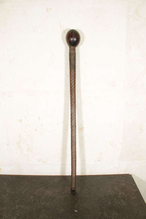 This large Zulu carved wood knobkierrie club has a cylindrical shaft wrapped with interwoven brass and copper wires ending with a spherical head.<br />
Knobkierrie were an indispensable weapon of war and hunt, particularly among southern Nguni