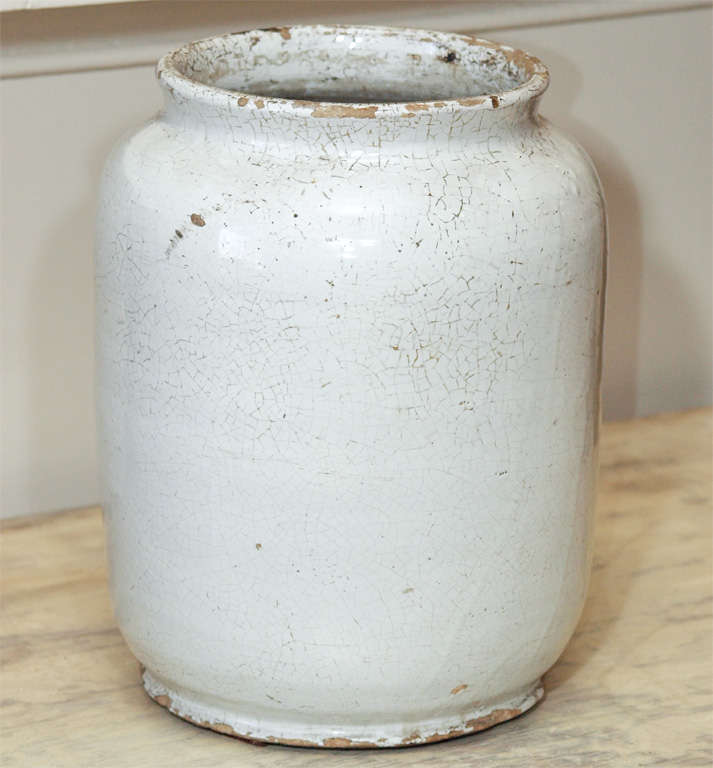 A large jar with scrolling lip and a wreath form cartouche centered with a petaled flower.