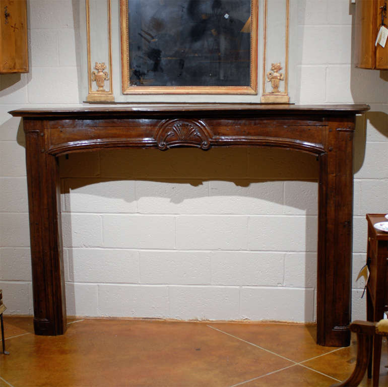 A French oak mantle with rich patina and central shell carving. 
