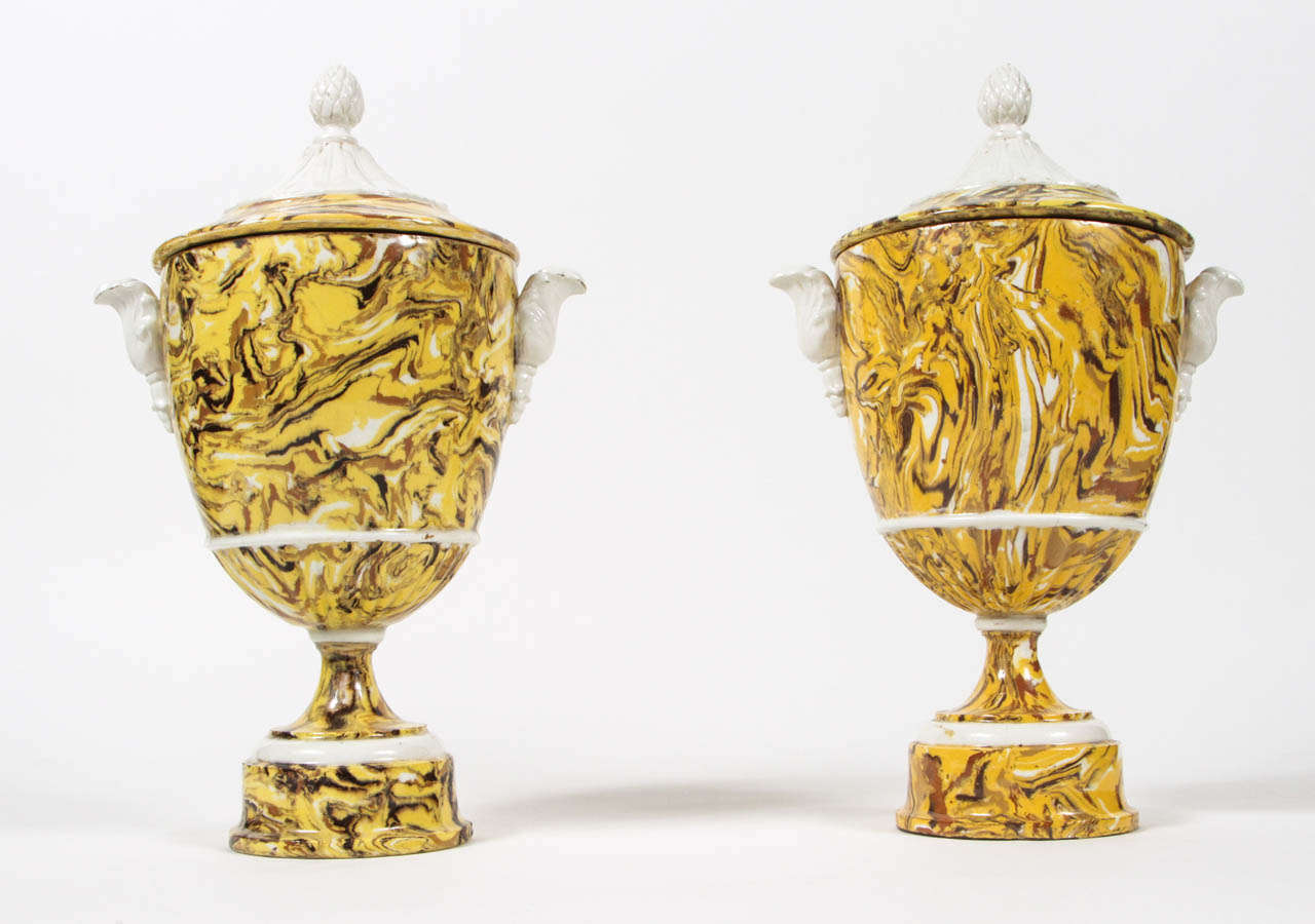 Two exquisitely marbleized pottery urns with contrasting faience accents.  Yellow ochre, mixed earth aptware in style of Provence, France. Details include pineapple finials, scroll handles and round pedestal base.  Late 19th century.  Made in Italy.