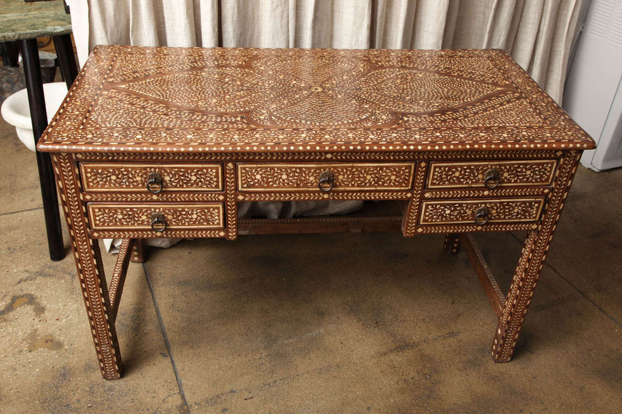 A bone inlaid desk from India.  A traditional Indian pattern of bone inlays cover the top, stretchers, and all sides. Five drawers.