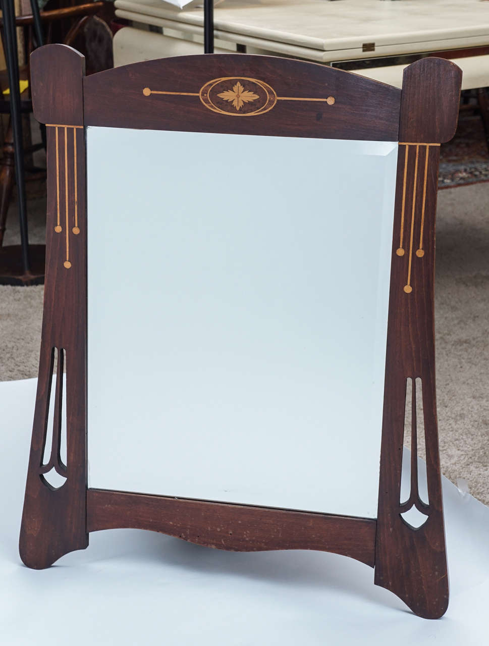 Stunning shape on this early 20th century frame with later beveled mirror. There are at least two additional woods in the inlaid motif. Cut-out design is reminiscent of the Scottish influence on Arts and Crafts design.