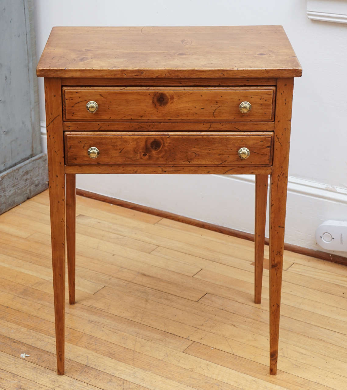 This simple side table is highlighted by four brass knobs and simple lines. The French pine is a bit more red than the mustard color English pine and this is an elegant end or side table.