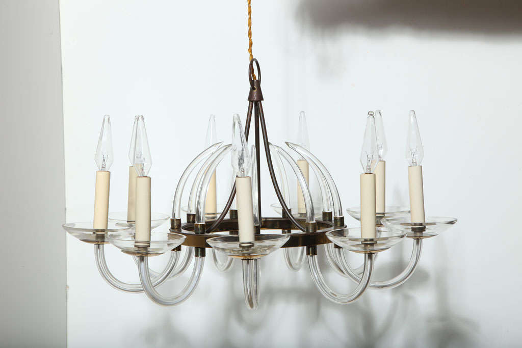 Modernist Marie Therese style hand blown transparent Clear Crystal Candlestick Chandelier. Featuring a single tier, nine scrolled crystal arms, nine cream candlesticks with nine round clear crystal drip bowls. Supported by a patinated brass center