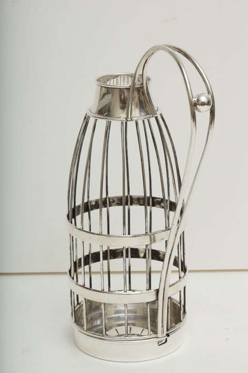 A German silver (800) bottle holder by Schnauffer.  Caged design with a large stylized handle featuring a round ball in the center. Signed 