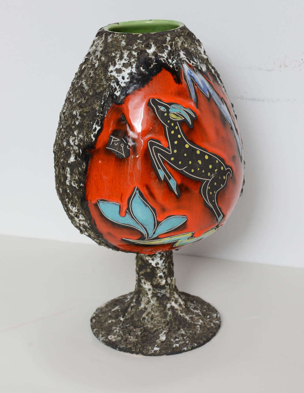 From the well-known house of ceramic work Pugi in Monaco comes this textural and colorful chalice piece.  Coloring and style clearly reflect 1960s design.  Piece features a deer leaping over grass with a mountain at its back, and leaves on its