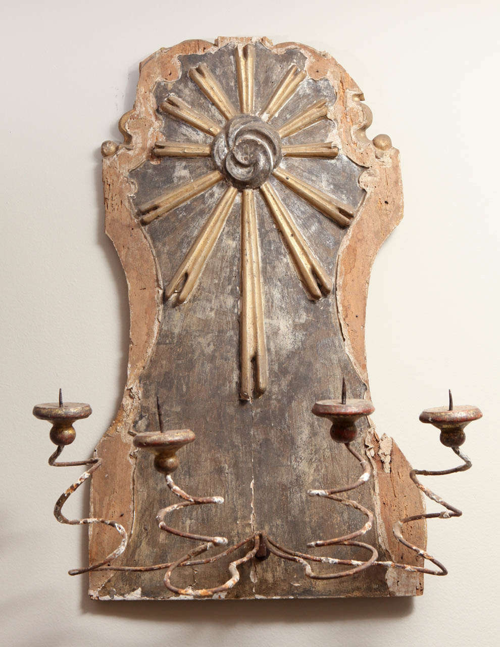 This is an 18th century fragment of a sunburst. It is painted and carved wood. The four curly arms are candleholders. The fragment is from Italy and is fitted to be wall mounted.