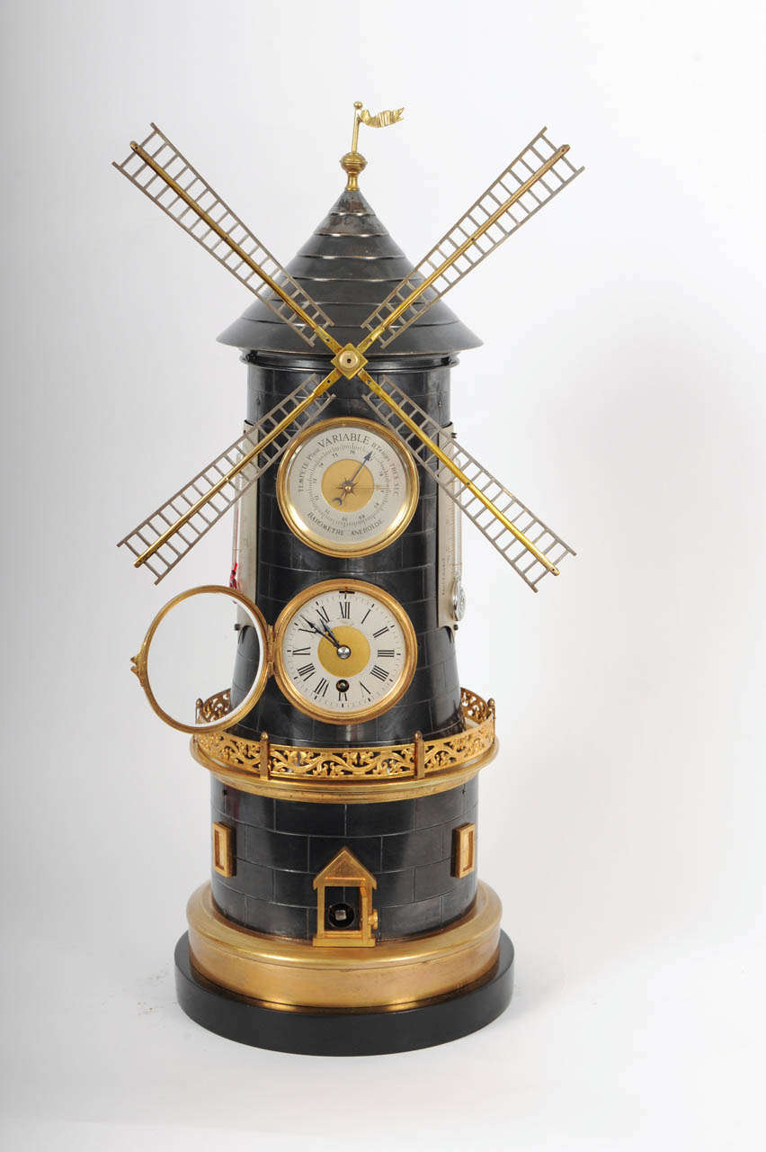 Case: brass, partly gilt, partly blued, black marble base, masoned wind mill, rotating wind mill vanes, hinged clock case, aneroid barometer, lateral thermometers with Reaumur and Fahrenheit units. Dial: silvered, radial Roman hours, gilt centre,