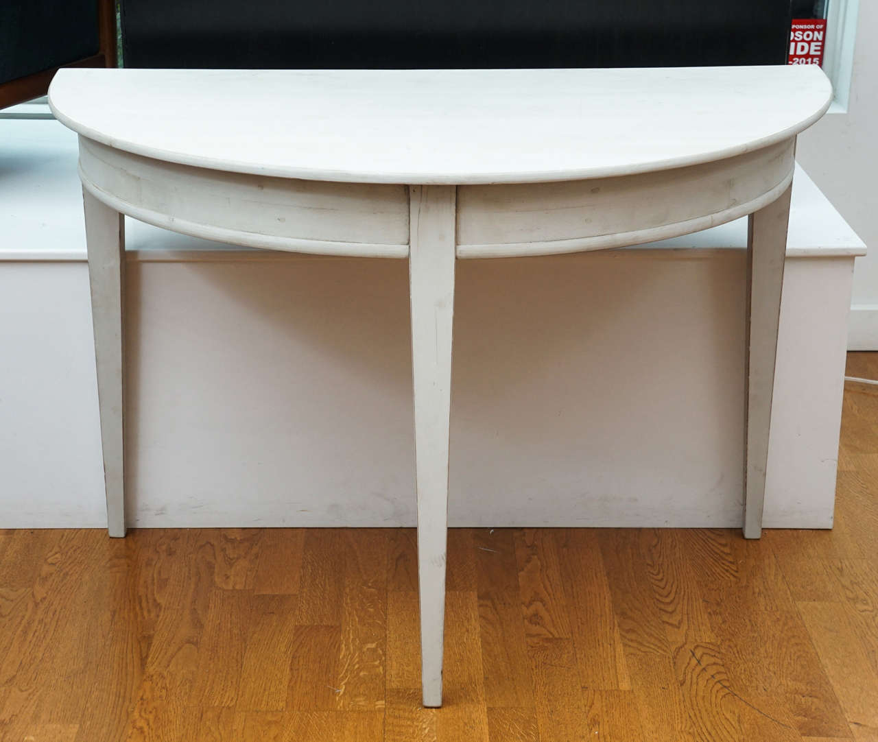 simple, elegant, demilune table in an oyster white, distressed, gustavian finish.
stands on three square tapered legs.