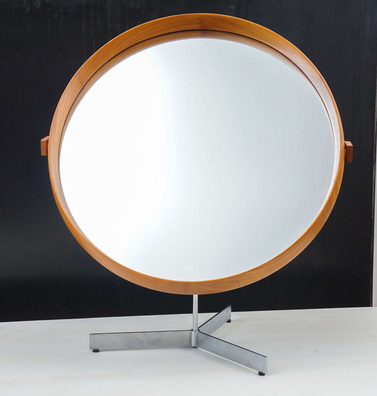 Large teak table mirror by Uno & Osten Kristiansson.
This handsome teak mirror, rotates and tilts on its brushed steel, tripod pedestal frame.