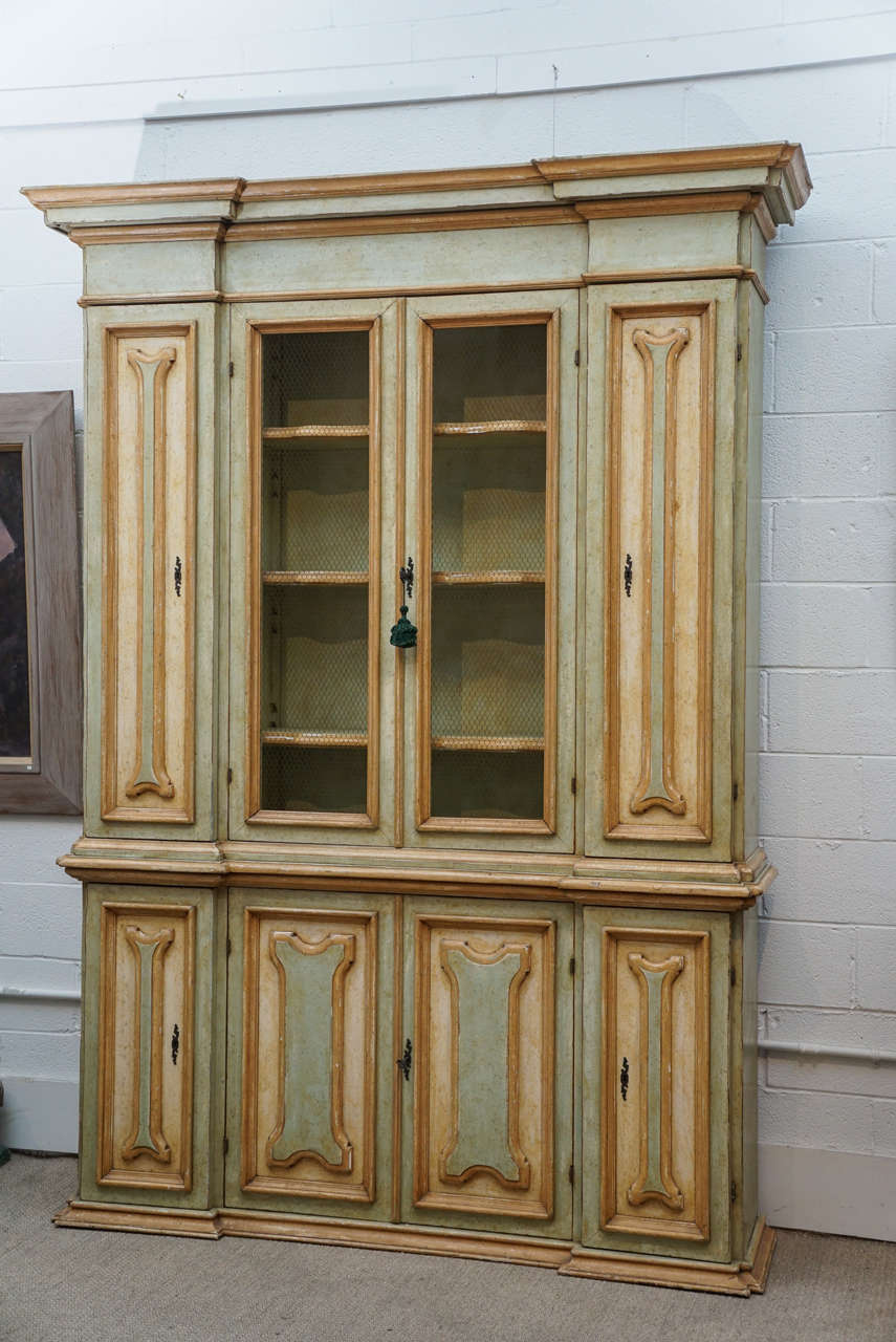 Here is a painted cabinet in the Italian Style. 
The top features an open front double door with chicken wire and closed side doors. This cabinet offers plenty of storage space with shelving.