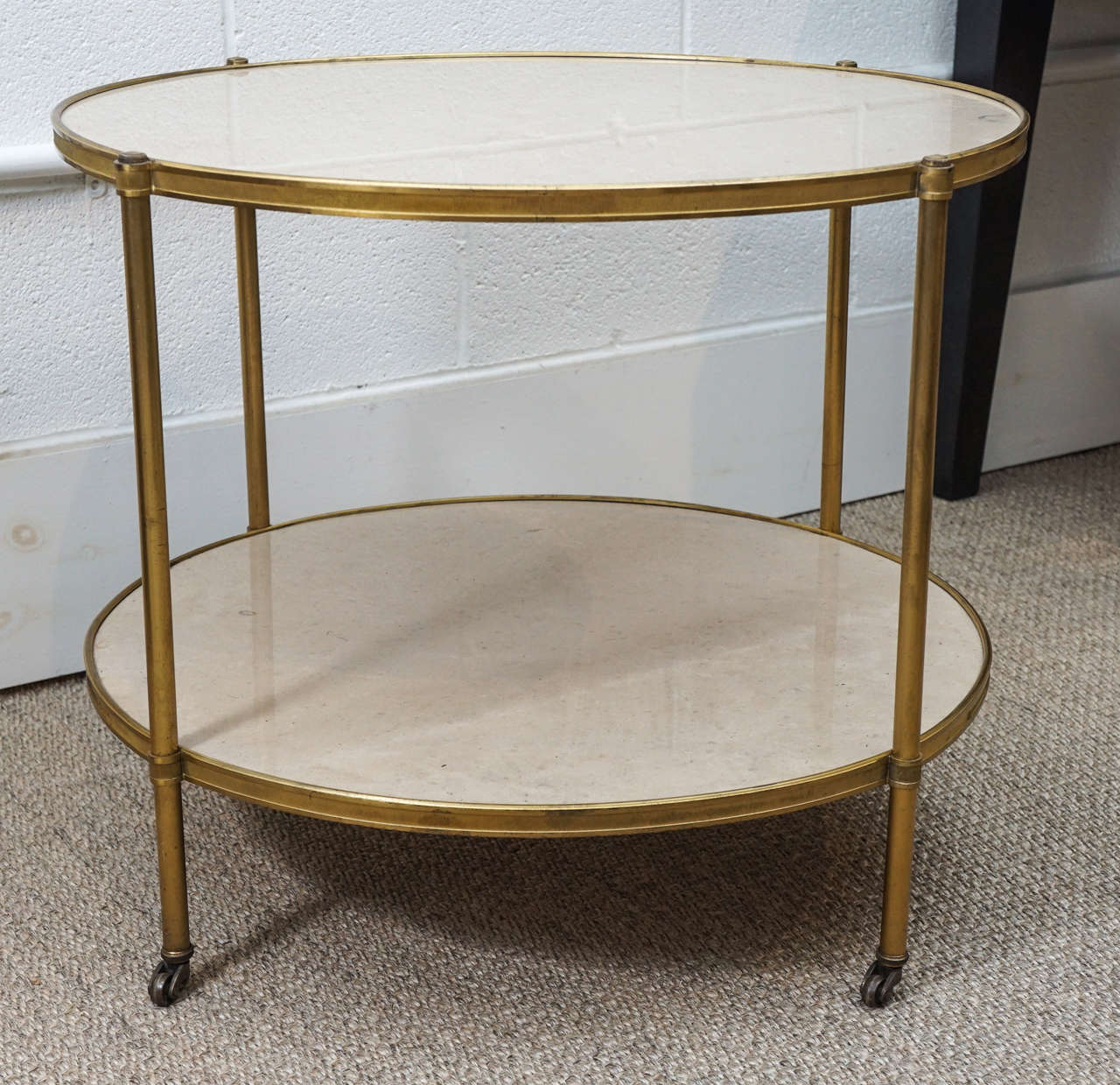 Here is a beautiful two-tiered marble table with solid brass surround and castered feet.