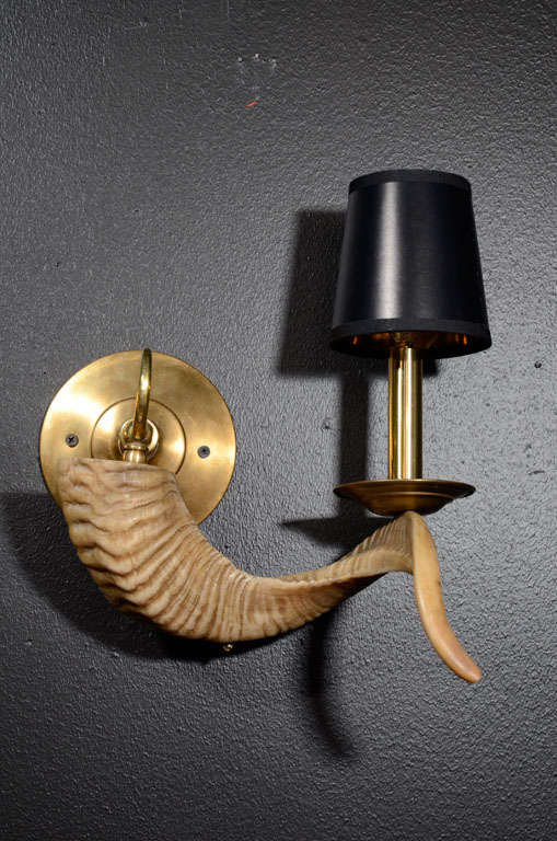 Pair of stylized ram horn

wall lights with patined 

brass fittings and circular

back plates with scrolled

details. Newly electrified,

and shown with black shades.