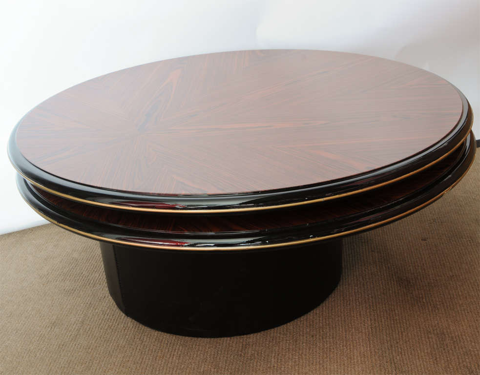 Double level, round coffee table in stunning, highly polished wood.  Second level rotates very smoothly to create a split-level, extended effect.  Both wood tops have been crafted to create an off-center starburst effect.  Edges of tops have light