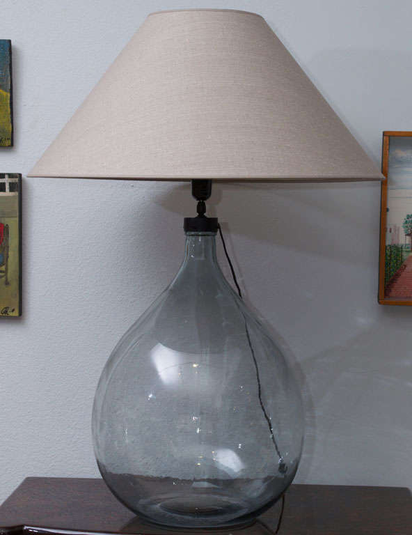A clear glass bottle made into a table lamp with custom shade