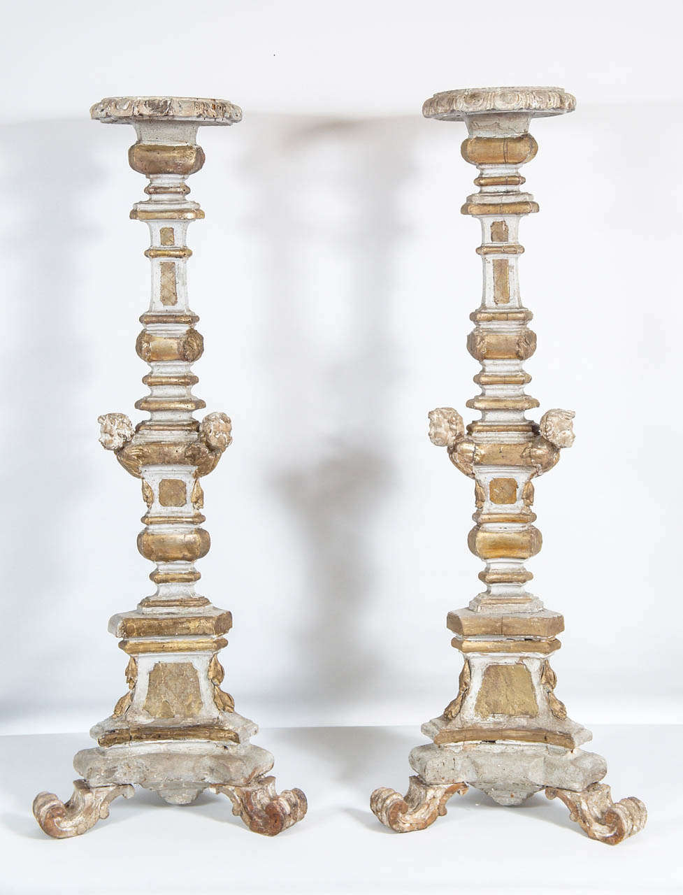 Sobresalientes palos de altar italianos del s. XVIII, de madera tallada y dorada, con remates circulares, decoración de putti aplicada tallada y pies con volutas.  Algunas pérdidas de pintura, reparaciones y diversos daños por