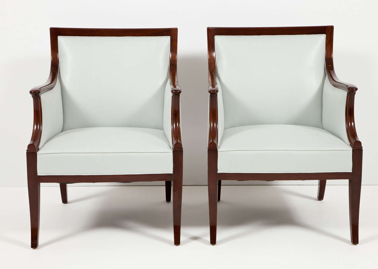 A pair of Danish rich mahogany armchairs by Frits Henningsen, circa 1940, with a slightly curved rectangular backrest, downswept armrests on scrolled supports raised on sabre legs.